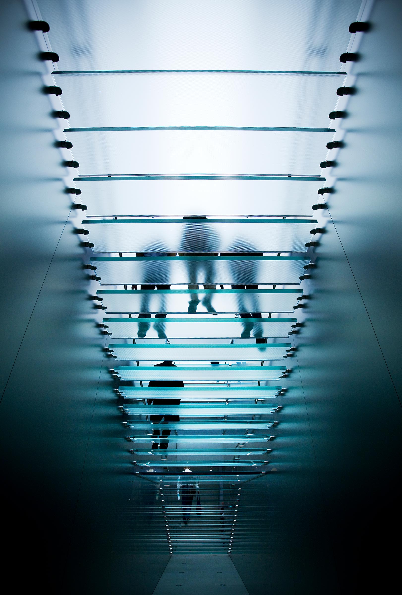 Architectural interior creative photography silhouettes of 5 people walking down opaque glass stairs